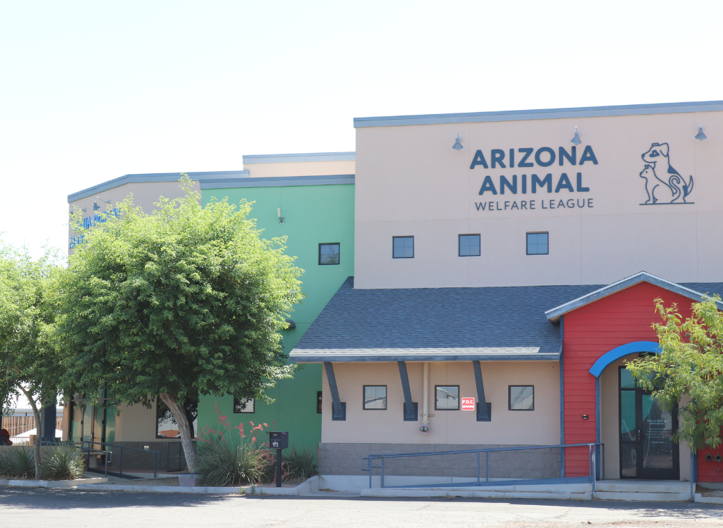 Front exterior of the AAWL Sonia Breslow Adoption Center, a single-story building with the Arizona Animal Welfare League sign over a teal entrance and a 'Welcome' banner