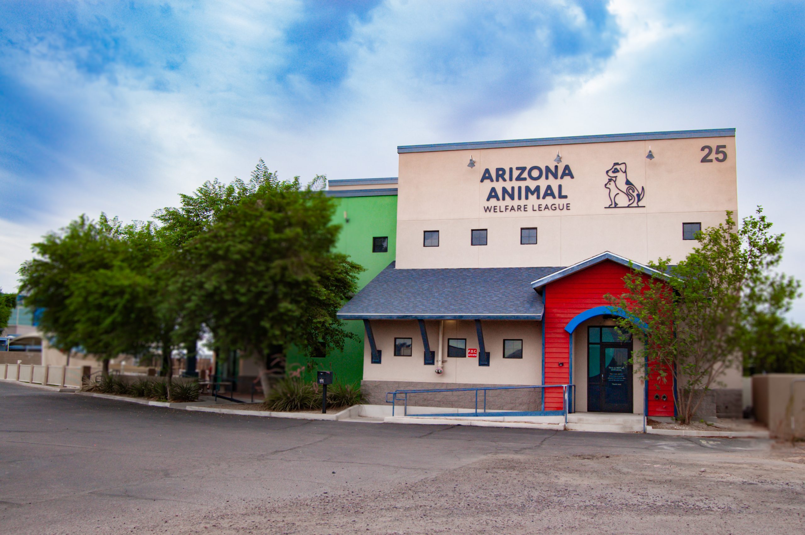 Exterior of the Arizona Animal Welfare League building with tan, green and red panels and a dog-and-cat logo
