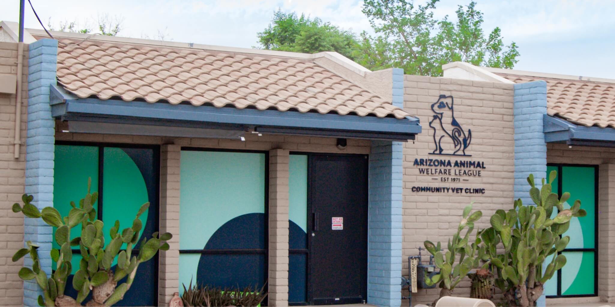 Exterior de la Clínica Veterinaria Comunitaria de AAWL, con ventanas turquesa y jardinería desértica